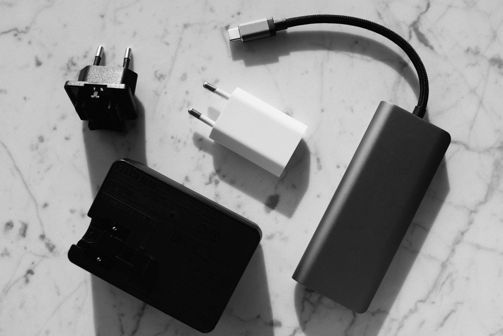 A set of electronic charging accessories including wall plugs and a USB-C hub, neatly arranged on a marble surface.